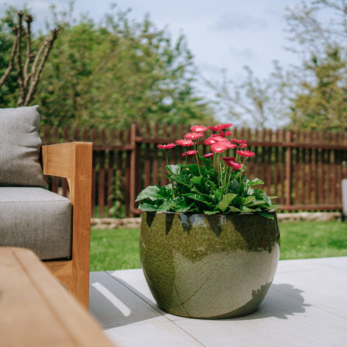 Pot ROMULUS rond 55x38 cm vert tropical en terre cuite émaillée, fleurs roses sur terrasse