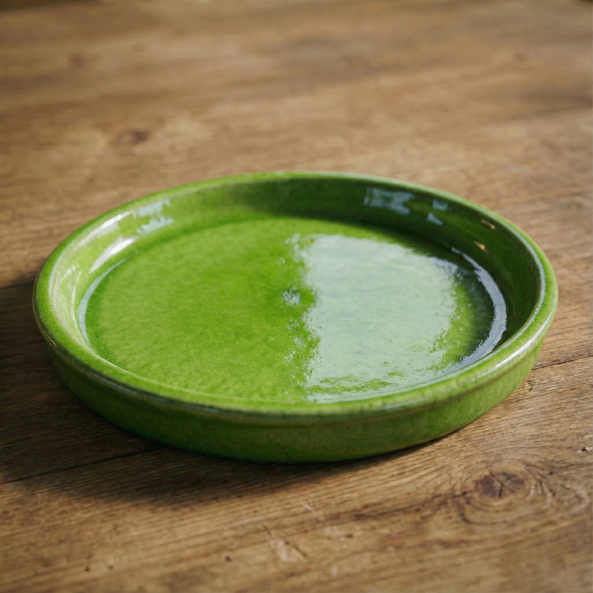 Apple green saucer, three-quarter view on a wooden table