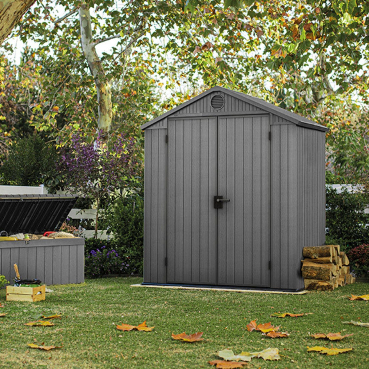 Abri de jardin DARWIN 6x4 gris fermé sur une pelouse, entouré d'arbres