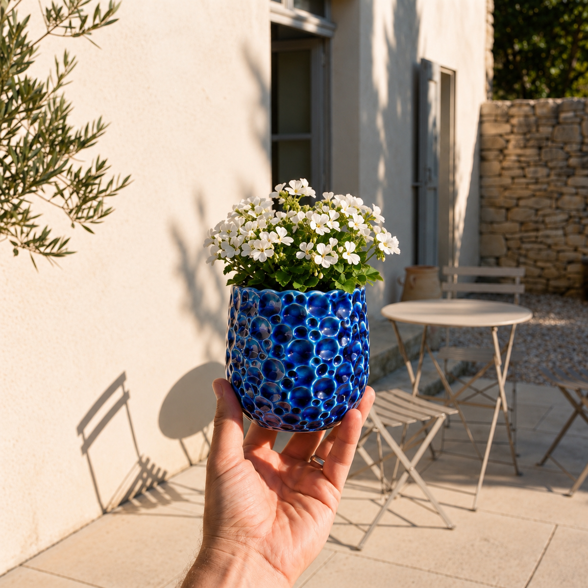 Ronde plantenbak PARISETTE 12x10 cm Blauw van geglazuurd keramiek, met witte bloemen op het terras