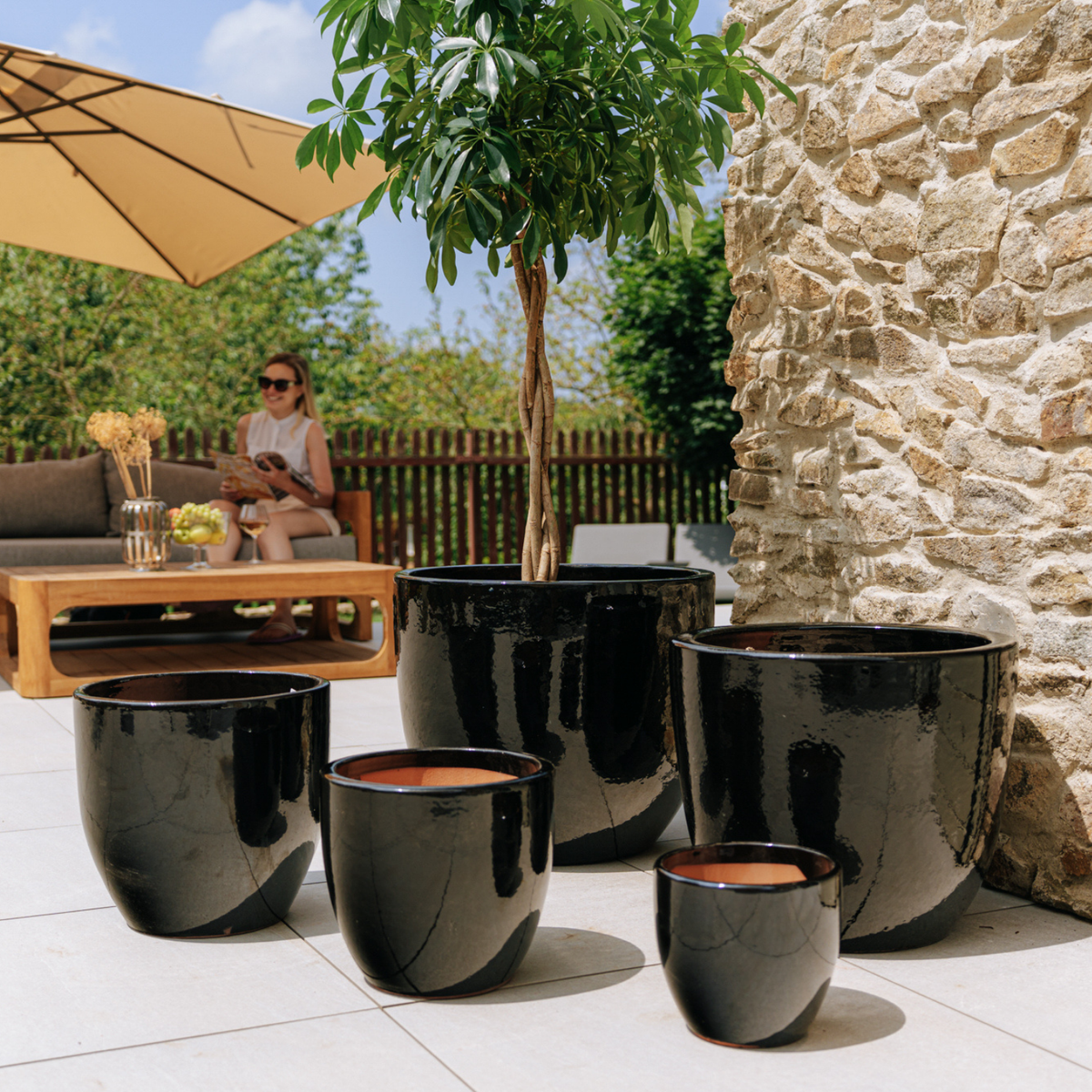Decoratieve plantenbak Lancelot 21x19 cm zwart van geglazuurd keramiek, tussen meerdere plantenbakken op het terras