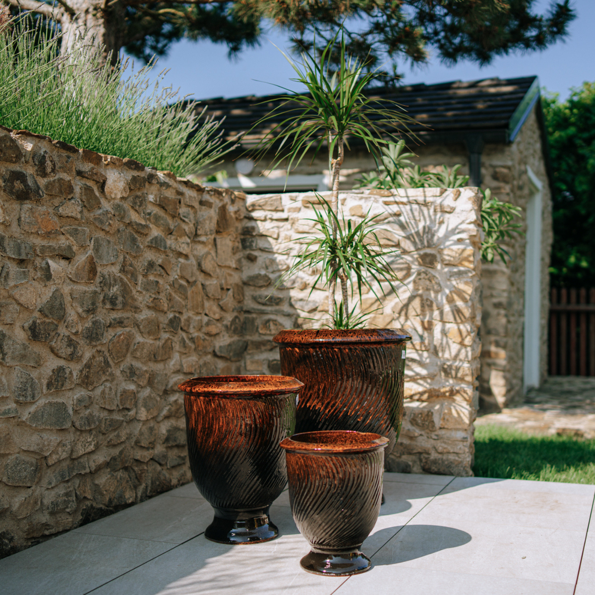 Pot Morgane avec pied 32x39 cm noir et orange en terre cuite émaillée, parmi trois pots sur terrasse