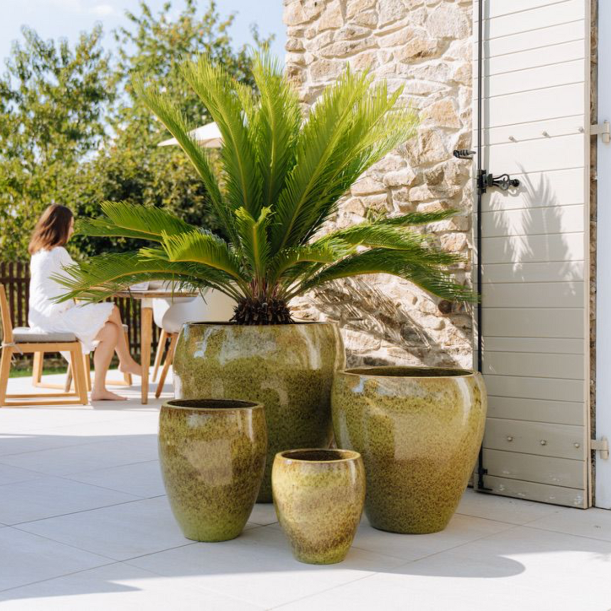 Vaso LAFONTAINE rotondo verde lago in ceramica smaltata, su terrazza con pianta verde