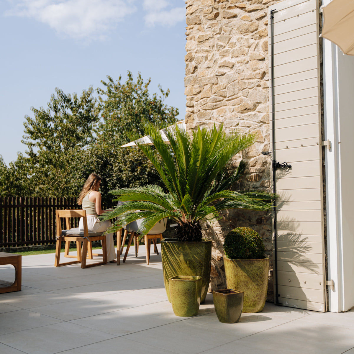 Pot Vauban rectangle vert de lac en terre cuite émaillée, sur terrasse avec palmier