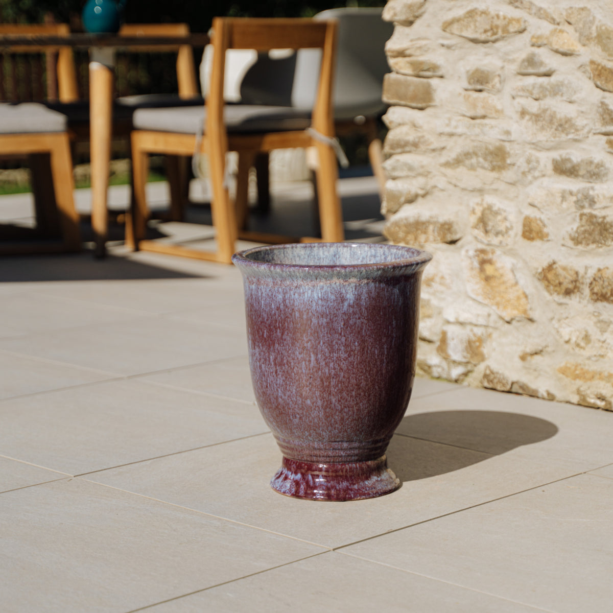 Plantenbak Arthur met voet 32x39 cm lichtviolet van geglazuurd keramiek, geplaatst op een terras