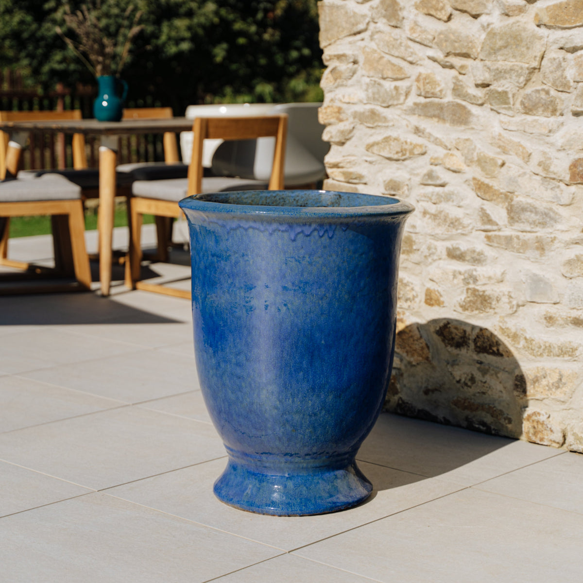 Plantenbak Arthur met voet 55x69 cm ultramarijnblauw van geglazuurd keramiek, leeg op een stenen terras