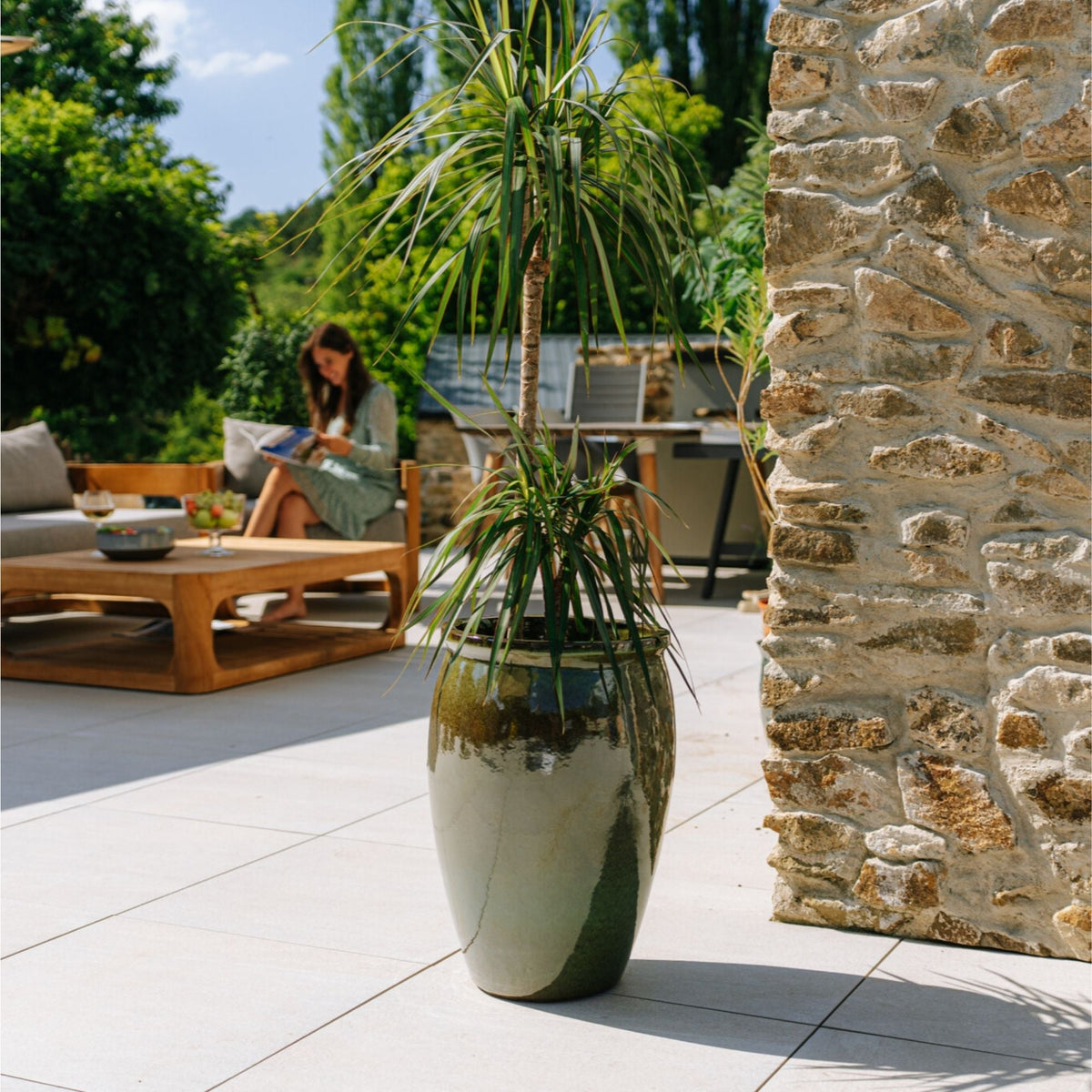 Bacchus amphora-shaped planter 36x52 cm Tropical Green in glazed ceramic, with a plant on a terrace
