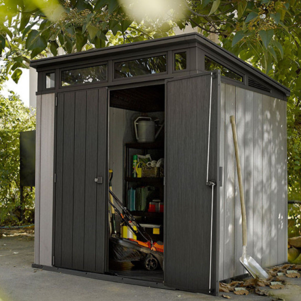 Abri ARTISAN gris avec une porte entrouverte dans un jardin