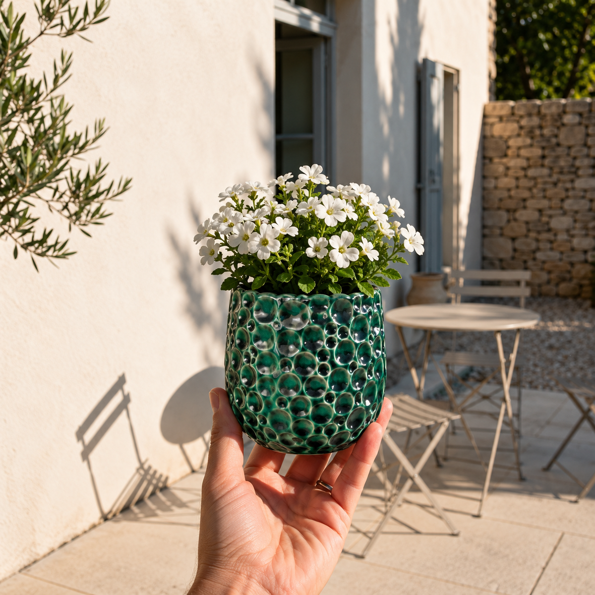 Ronde plantenbak PARISETTE 12x10 cm Bosgroen van geglazuurd keramiek, gevuld met witte bloemen op het terras