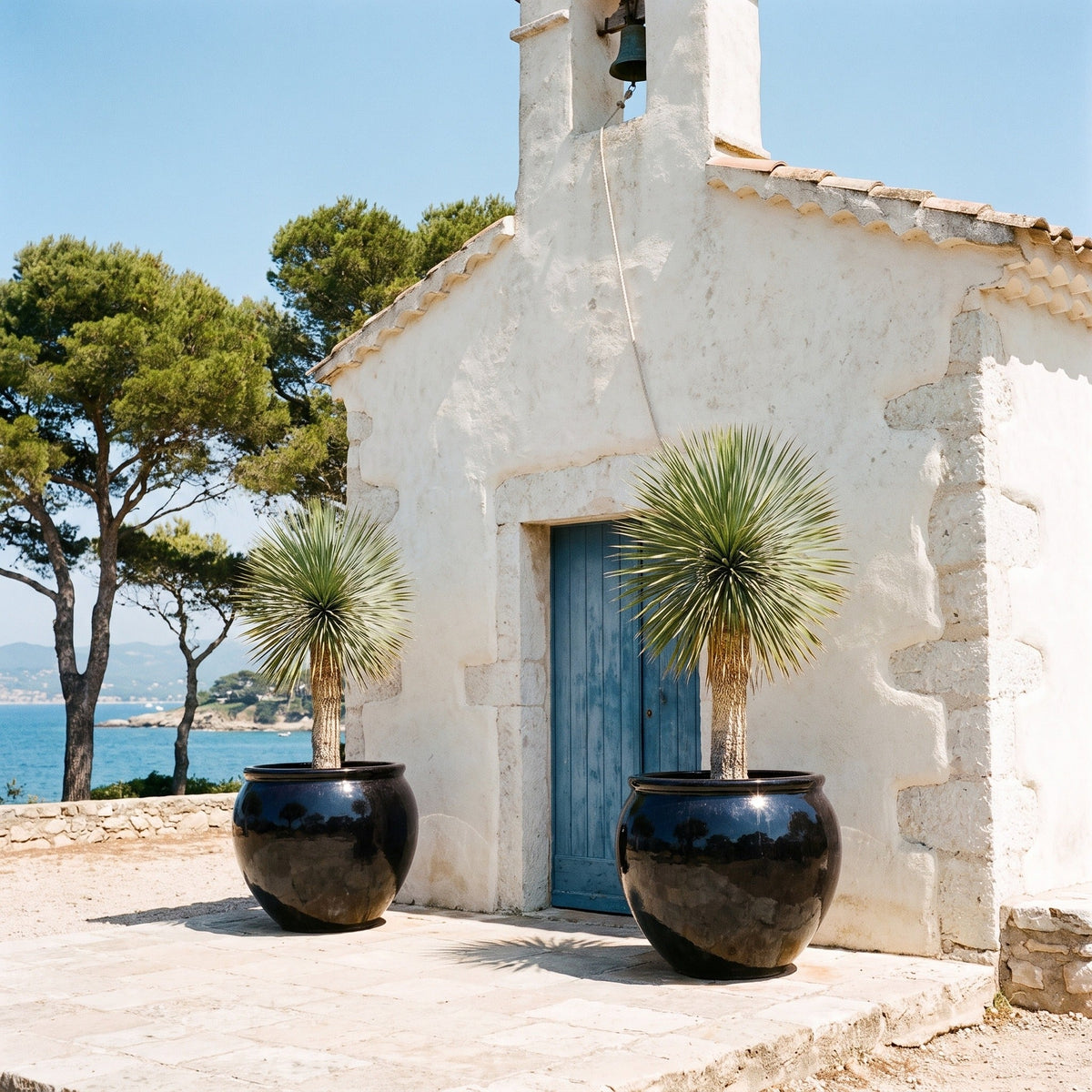 Pot LUTECE rond 86x64 cm noir en terre cuite émaillée, planté d’un yucca devant une chapelle