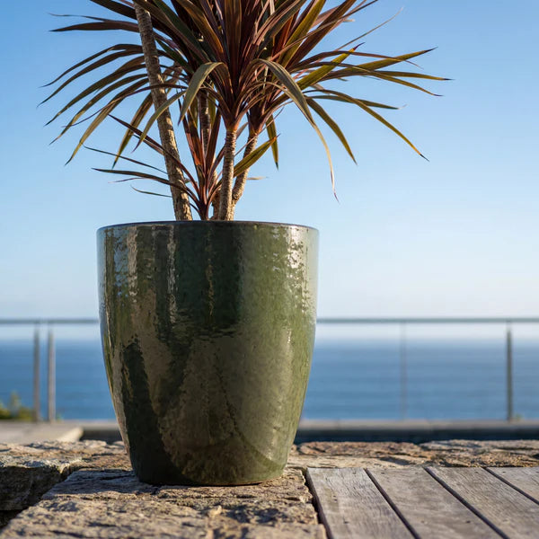 Macetero Mazarin2 Verde intenso de cerámica esmaltada, plantado con una drácena frente al mar
