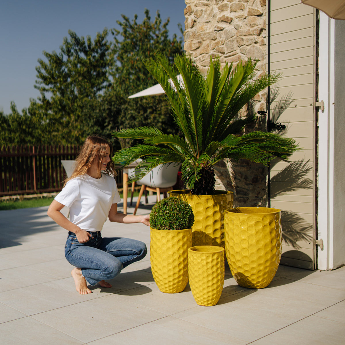 Vaso Merovee a forma di anfora giallo in ceramica smaltata, su una terrazza con piante