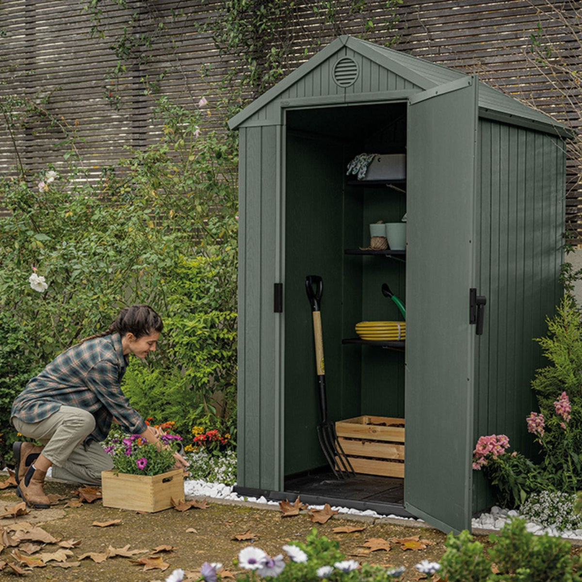 Abri de jardin DARWIN 4x4 vert ouvert avec outils rangés, dans un jardin