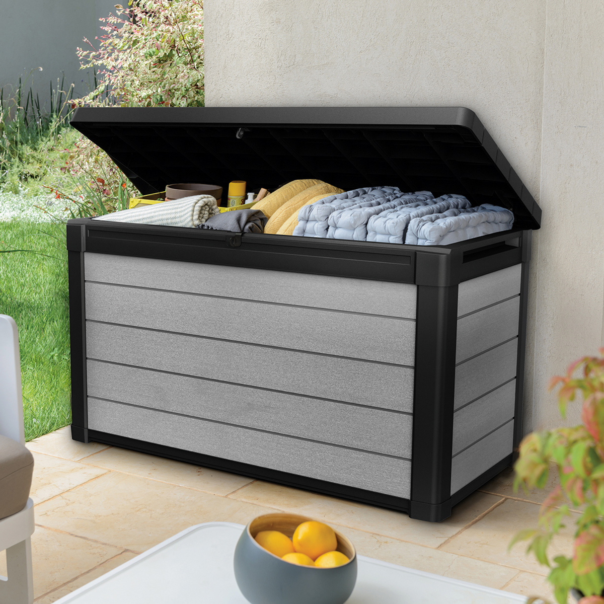 Coffre Denali DuoTech gris ouvert avec coussins sur une terrasse