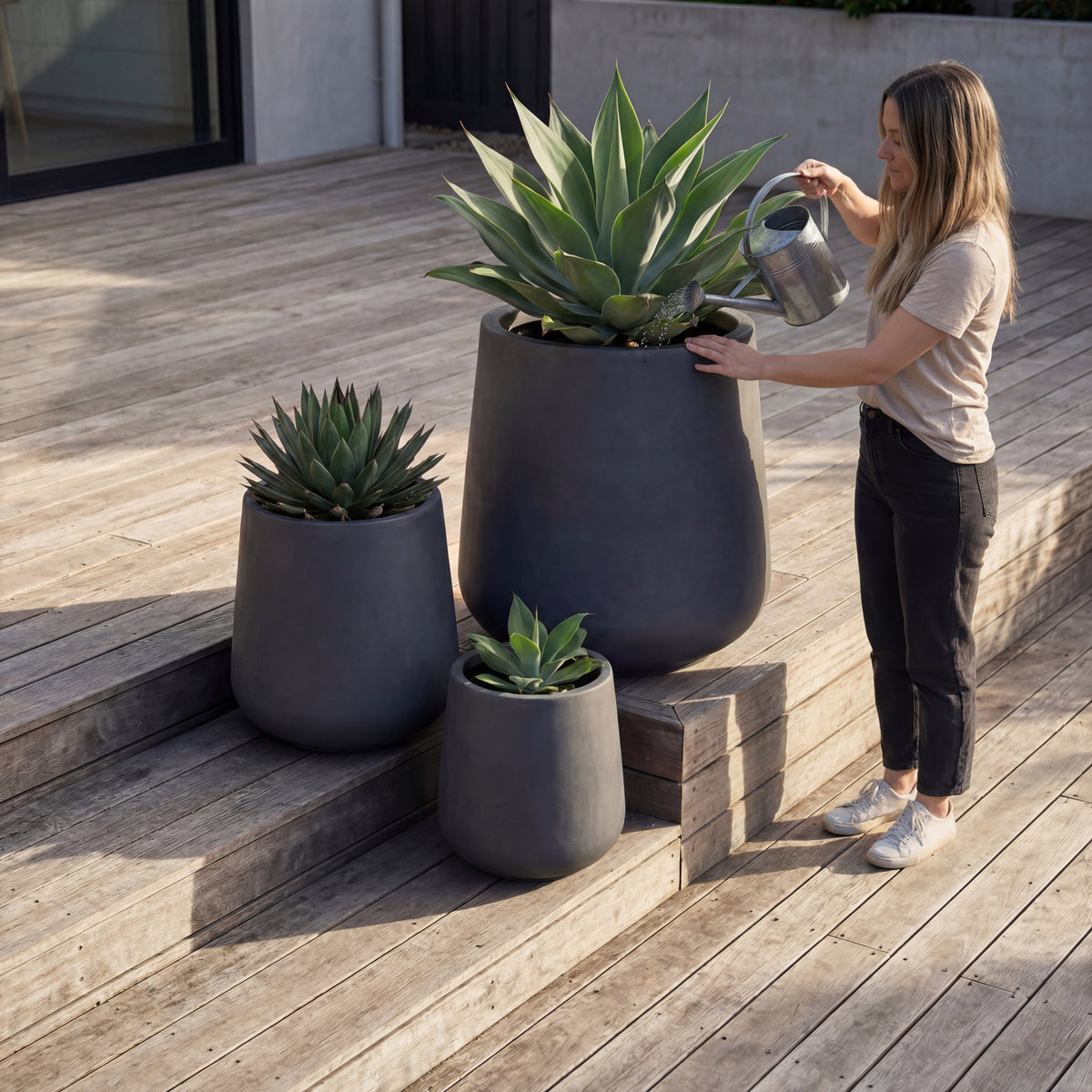 Portavaso preforato Silex Grigio scuro in calcestruzzo fibrorinforzato, annaffiato da una donna su terrazza