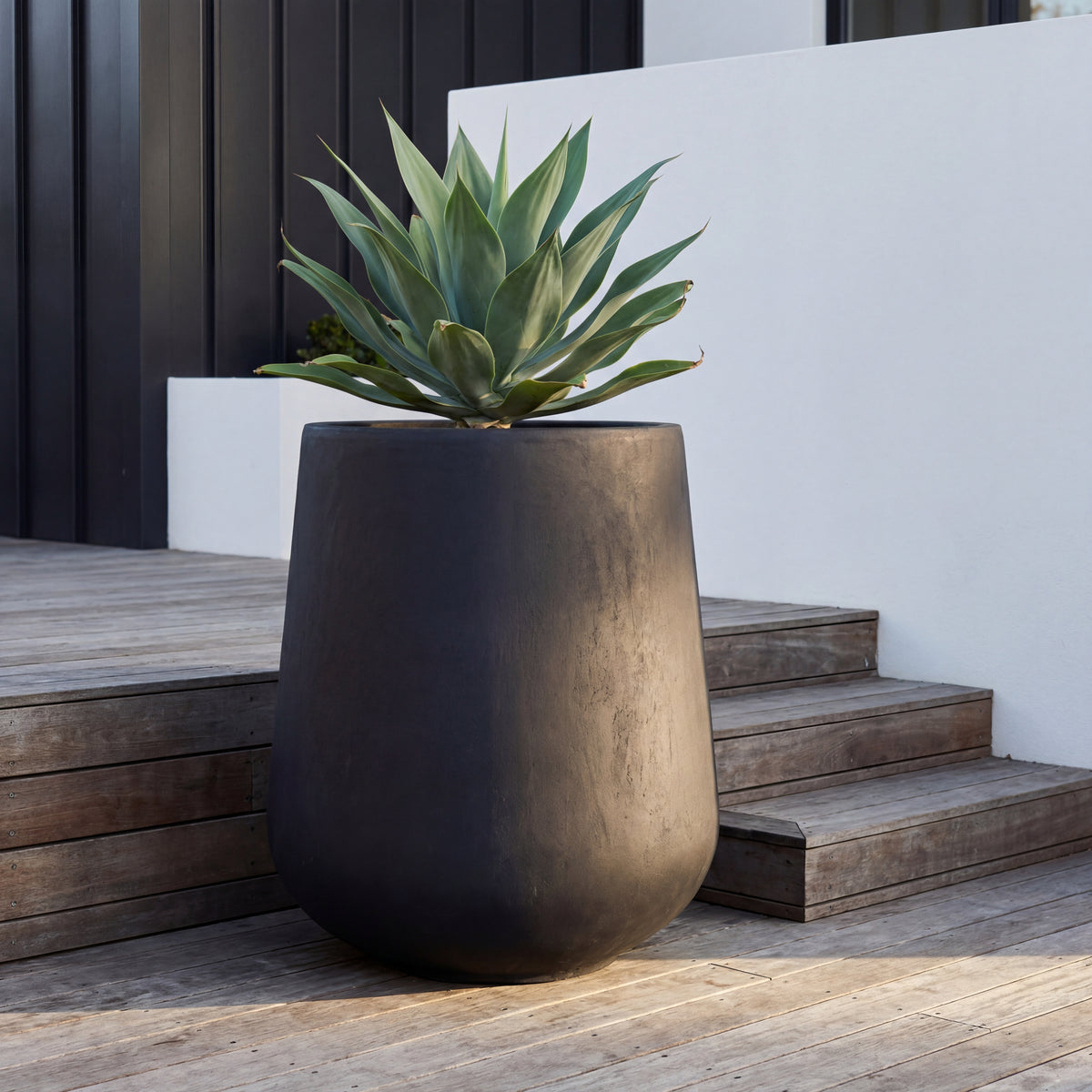 Pre-drilled Silex cachepot matt black in fibre concrete, with agave on a wooden terrace