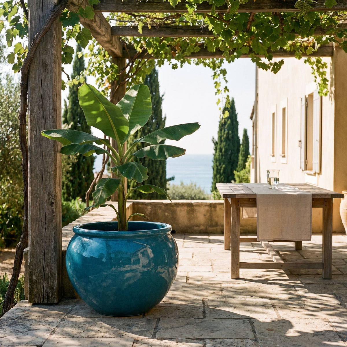 Round LUTECE planter 86x64 cm in Caribbean Blue glazed ceramic, with a banana tree under a pergola