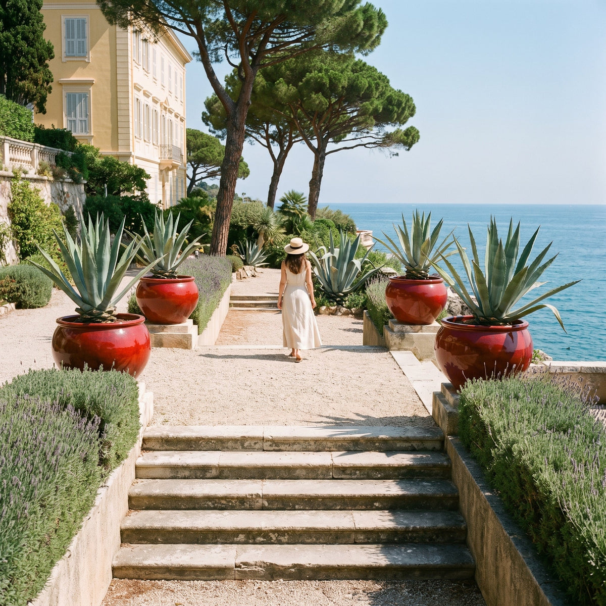 Round LUTECE planter 86x64 cm in Tropical Red glazed ceramic, with agaves in a coastal garden
