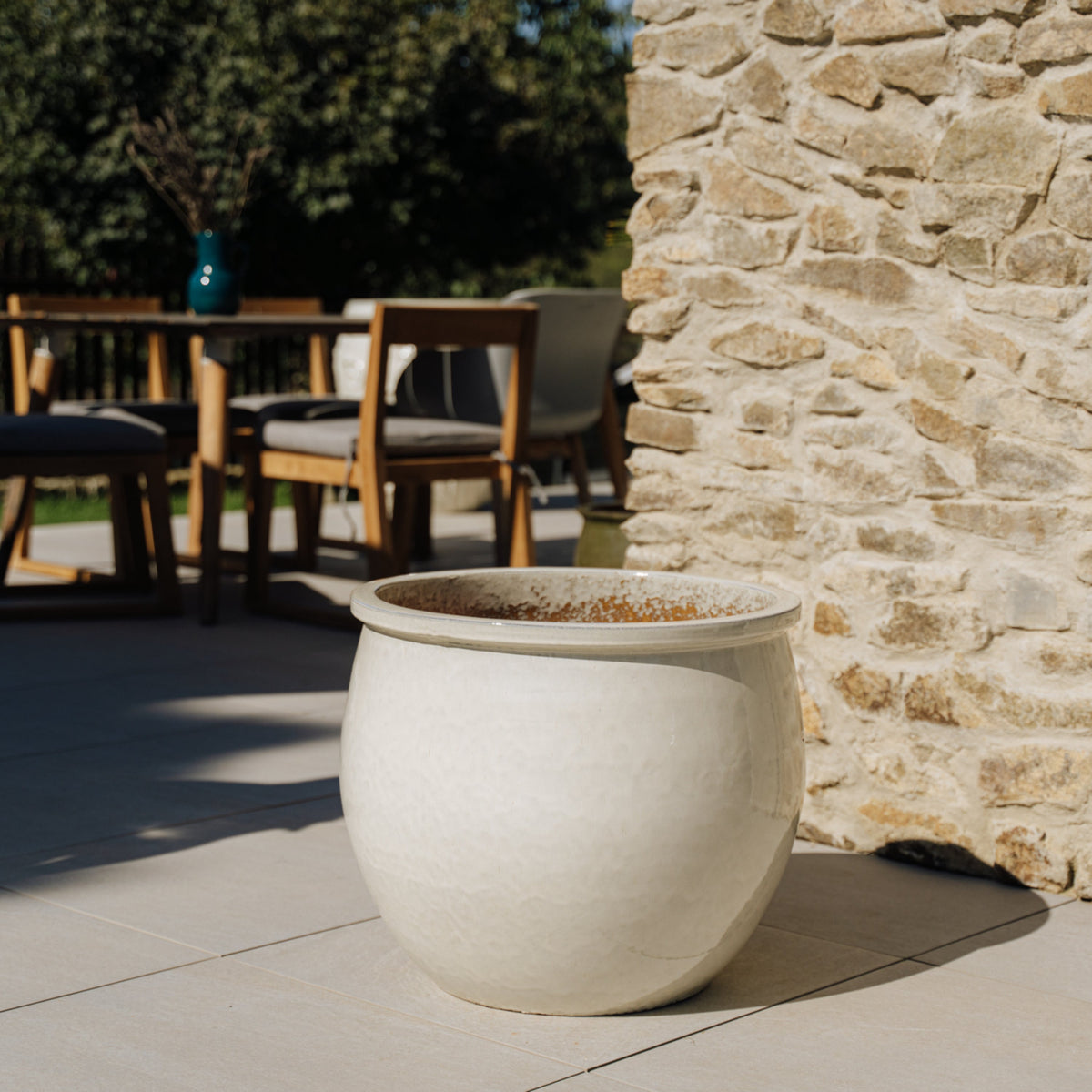 Pot Newton rond 55x46 cm crème en terre cuite émaillée, vide sur une terrasse