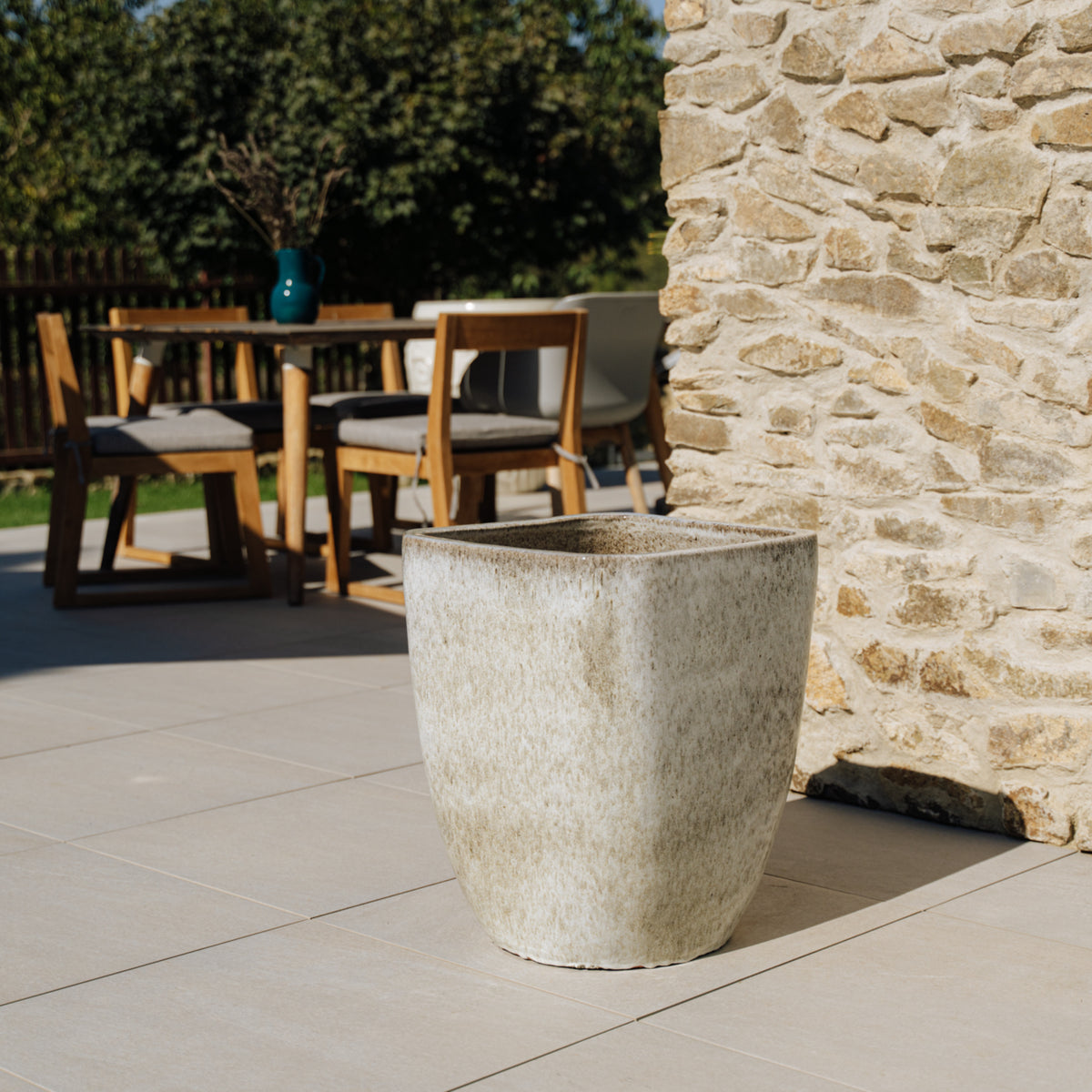 Macetero rectangular Vauban de 34 × 43 cm, Blanco atigrado, de cerámica esmaltada, vacío junto a una mesa de exterior